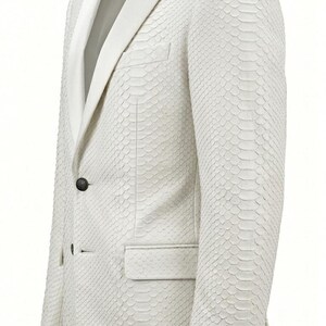 May include: A white blazer with a textured, scale-like pattern. The jacket features a notched lapel, a single-button closure, and a pocket on the front. The sleeves have four buttons at the cuff. The blazer is a formal garment.