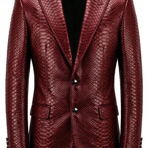 May include: A burgundy blazer with a snakeskin pattern. The jacket has a notched lapel, two front pockets, and two silver buttons. The sleeves have three buttons. The blazer is a formal style.
