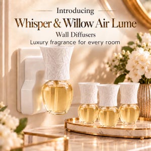 May include: Whisper & Willow Air Lume wall diffusers featuring white textured tops with leaf patterns and clear glass bases filled with golden fragrance oil. One diffuser is plugged into a wall outlet, while three others sit on a marble tray.