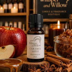 May include: A bottle of Caramel Apple fragrance oil from Whisper and Willow, with a black cap and a white label. The image includes a red apple, cinnamon sticks, star anise, and a small bowl of caramel. The label reads "CARAMEL APPLE FRAGRANCE OIL 10 ML."
