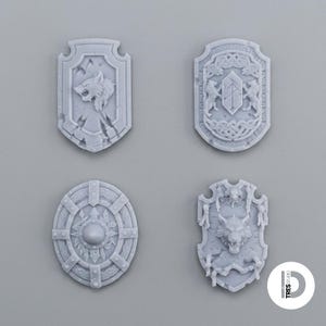 May include: Four light gray miniature shields with intricate relief designs. One features a wolf head, another displays two lions flanking a central crest, one is a circular riveted shield, and the last shows a wolf head with skeletal accents.