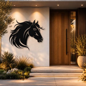 May include: A black metal wall art piece shaped like the head and flowing mane of a horse. The silhouette features sharp, stylized lines defining the facial structure, ears, and long, sweeping hair, mounted on a light-colored exterior wall.