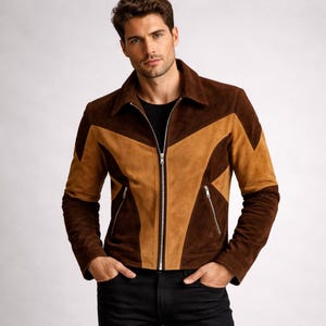 Op de afbeelding: Bruin en beige suède jasje met ritssluiting en twee voorzakken. De jas heeft een geometrisch ontwerp en een kraag. De mouwen zijn lang en de jas wordt gedragen met een zwarte broek.