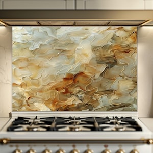 Op de afbeelding: Een decoratieve keukenachterwand met een abstract ontwerp. Het kunstwerk toont vloeiende patronen in tinten beige, bruin en wit, waardoor een marmereffect ontstaat. De achterwand is geïnstalleerd achter een gasfornuis en voegt een stijlvolle touch toe aan de keuken.