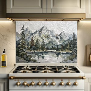 Peut inclure: Une crédence en mosaïque représentant un paysage de montagne avec un lac et des arbres à feuilles persistantes. L'œuvre utilise des nuances de gris, de vert et de blanc, créant une scène naturelle et sereine. La crédence est installée au-dessus d'une cuisinière blanche.
