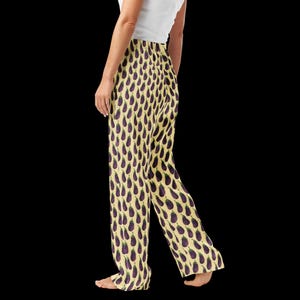 May include: Wide-leg pajama trousers featuring a repeating pattern of purple aubergines on a pale yellow backdrop. The trousers are made of a soft, flowing fabric. The person is wearing a white top.