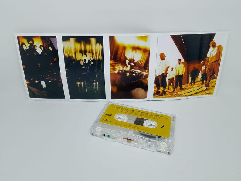 May include: A clear cassette tape with a yellow label and the number 2 is in the foreground. Behind it is a folded album cover with several images of people in various settings, with a warm color palette.