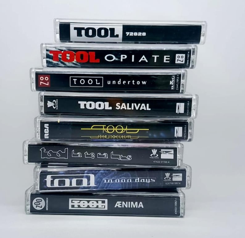 May include: A stack of Tool cassette tapes. The tapes have black and white labels with the band's name and album titles, including "Opiate," "Undertow," and "&AElig;nima." The cases are clear plastic.