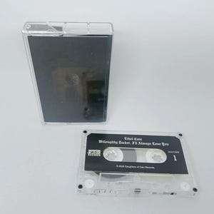Puede incluir: Una cinta de cassette transparente con una etiqueta negra que dice "Ethel Cain Willoughby Tucker, I'll Always Love You". La cinta está en una caja de plástico transparente. La etiqueta también incluye el texto "Daughters of Cain Records".