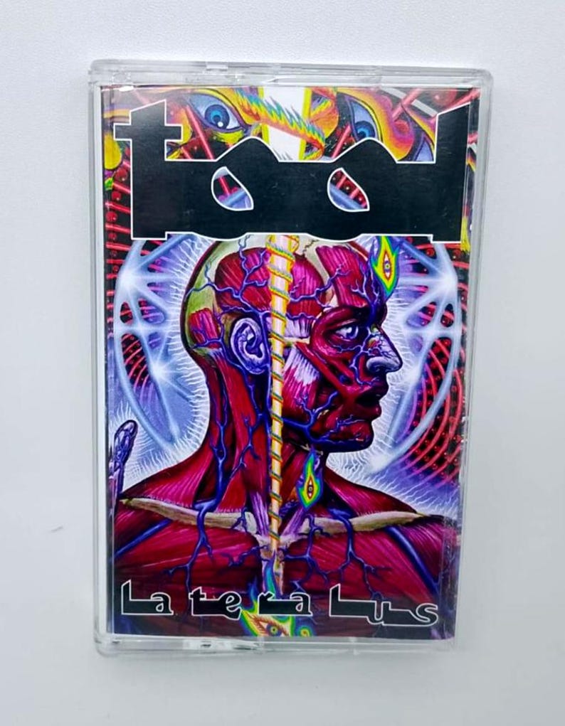 May include: A cassette tape featuring the band Tool's logo in black and a vibrant, surreal illustration of a human head with exposed muscles and veins. The album title, "Lateralus," is printed in white.