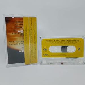 May include: A clear cassette tape case with a yellow label featuring the text "WU-TANG CLAN - ENTER THE WU-TANG (36 CHAMBERS)". The cassette is next to its case, which has a matching yellow spine and album art.