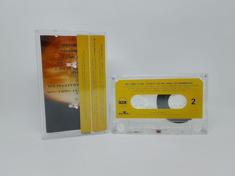 May include: A clear cassette tape case with a yellow label featuring the text "WU-TANG CLAN - ENTER THE WU-TANG (36 CHAMBERS)". The cassette is next to its case, which has a matching yellow spine and album art.
