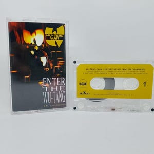 May include: A clear cassette tape case and cassette featuring the album "Enter the Wu-Tang (36 Chambers)" by the Wu-Tang Clan. The cassette has a yellow label with black text and the number 1.