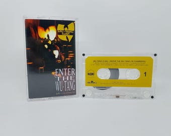May include: A clear cassette tape case and cassette featuring the album "Enter the Wu-Tang (36 Chambers)" by the Wu-Tang Clan. The cassette has a yellow label with black text and the number 1.