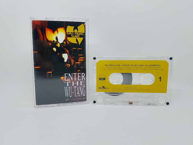 May include: A clear cassette tape case and cassette featuring the album "Enter the Wu-Tang (36 Chambers)" by the Wu-Tang Clan. The cassette has a yellow label with black text and the number 1.