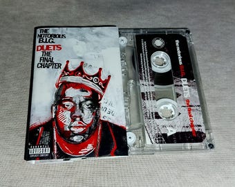 May include: A cassette tape with the album cover of "The Notorious B.I.G. Duets: The Final Chapter." The cover art features a red and black portrait of the artist wearing a crown. The cassette tape is clear with black text.