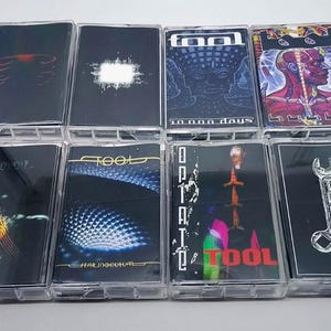 May include: Collection of Tool cassette tapes. Each tape features unique artwork, including images of a rib cage, a white shape, a face, a human figure, and a wrench. The tapes are in clear plastic cases.
