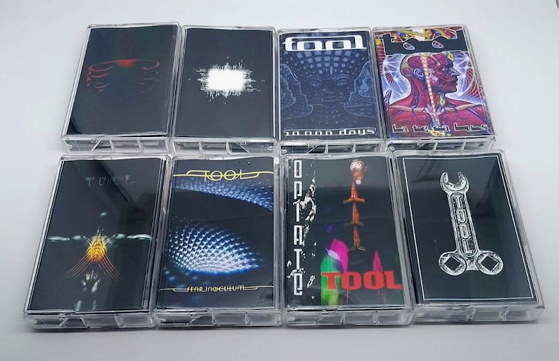 May include: Collection of Tool cassette tapes. Each tape features unique artwork, including images of a rib cage, a white shape, a face, a human figure, and a wrench. The tapes are in clear plastic cases.