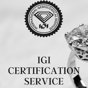 Könnte beinhalten: Nahaufnahme eines Diamantrings mit einem großen, klaren Edelstein. Der Ring ist vor einem weißen Hintergrund mit dem Text "IGI CERTIFICATION SERVICE" und dem IGI-Logo abgebildet. Das Diamond Dreams-Logo ist ebenfalls sichtbar.