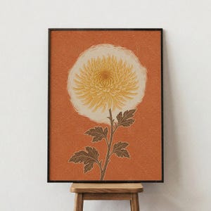 May include: A framed wall art print featuring a large, yellow chrysanthemum flower centered on a textured, burnt orange background with fine, swirling line patterns. The flower has a long, thin stem with dark green, serrated leaves.