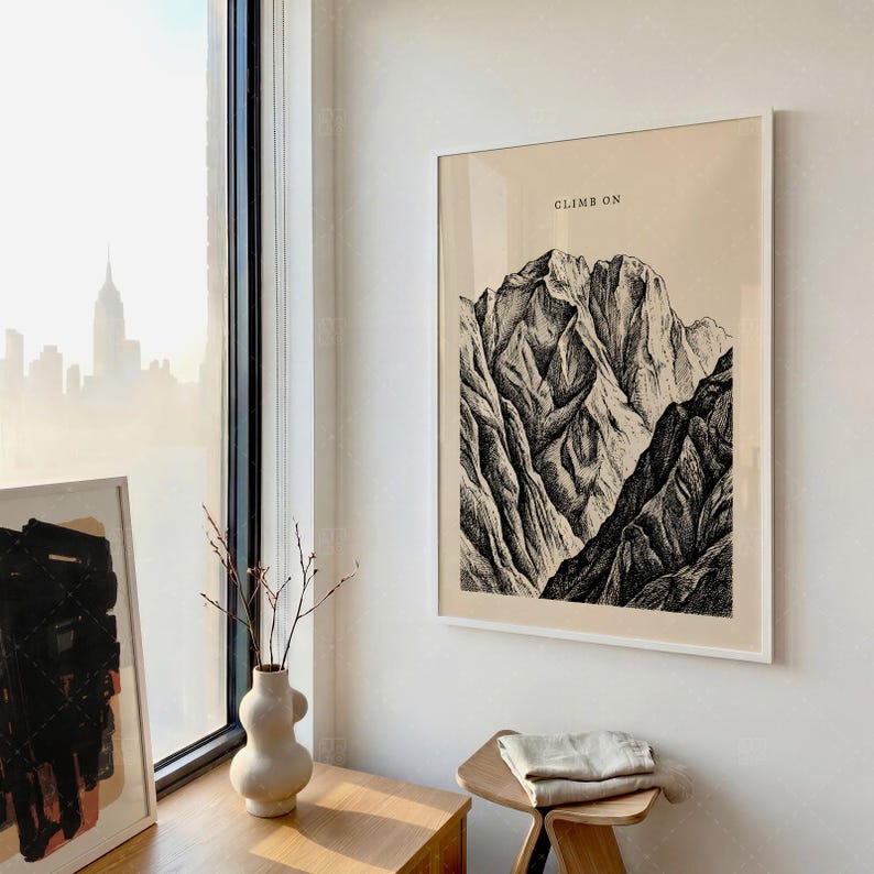 Climb On Mountain Print in frame on wall near window in minimalist office space with natural light, vintage mountain landscape poster, motivational adventure wall art with beige and black tones