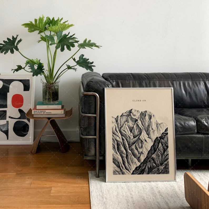 Climb On Mountain Print in frame on wall above leather sofa in contemporary living room, vintage mountain art poster with inspirational typography, nature landscape wall decor