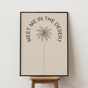 May include: Framed art print featuring a minimalist illustration of a palm tree. The artwork is in black and white, with the text "MEET ME IN THE DESERT" arched above the tree. The background is a neutral beige color.