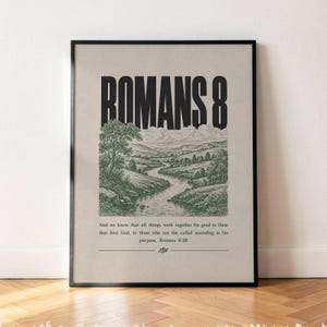 May include: A framed wall art print featuring the bold black text ROMANS 8 above a detailed green landscape illustration of a winding river through hills. Below the image, the text reads: And we know that all things work together for good to them that love God, to them who are the called according to his purpose. Romans 8:28.