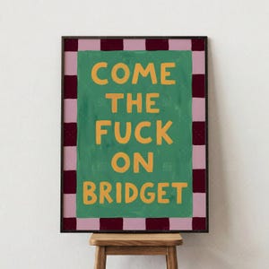 Come The Fuck On Bridget retro poster product detail closeup featuring bold orange typography on vibrant green background with pink and burgundy checkered border, humorous saying wall art print