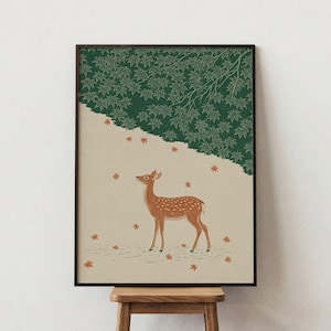 May include: A framed wall art print featuring a spotted deer standing on a light beige ground. Above the deer, a dense canopy of dark green maple leaves hangs down. Several small orange maple leaves are scattered across the beige space.