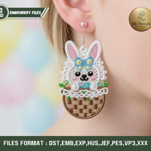 May include: Embroidered Easter bunny earrings with a basket design. The earrings feature a white bunny with pink ears, a blue bow, and colorful Easter eggs. The text "EMBROIDERY FILES" and "Silk Threadss" are visible. The image also includes the text "FILES FORMAT : DST, EMB, EXP, HUS, JEF, PES, VP3, XXX".