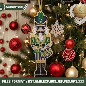 May include: A Christmas tree decorated with ornaments, including a nutcracker figure, red and gold baubles, and a snowflake. The nutcracker is green, gold, and blue. The text "EMBROIDERY FILES" is visible.
