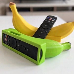 May include: A bright yellow banana-shaped remote control holder and a vibrant lime green banana-shaped remote control holder. Each holder features a rectangular slot designed to securely store a black television remote control in an upright position.