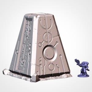 Pode incluir: Uma peça de terreno em miniatura em forma de pirâmide, cinza claro, com desenhos circulares e lineares gravados. Uma pequena figura azul de um soldado com uma arma está por perto. A peça de terreno tem uma aparência texturizada semelhante à pedra.