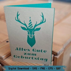Peut inclure: Carte de vœux d'anniversaire avec une tête de cerf turquoise portant un chapeau de fête, découpée dans du carton beige. Le texte allemand "Alles Gute zum Geburtstag" est en dessous. La carte est ouverte, révélant l'intérieur turquoise.