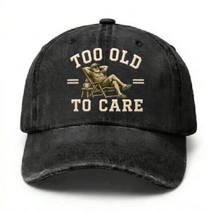 May include: A black baseball cap with a distressed finish featuring a graphic of a person relaxing in a chair with a mug. The text "TOO OLD TO CARE" is printed in beige capital letters above and below the illustration in a bold serif font.