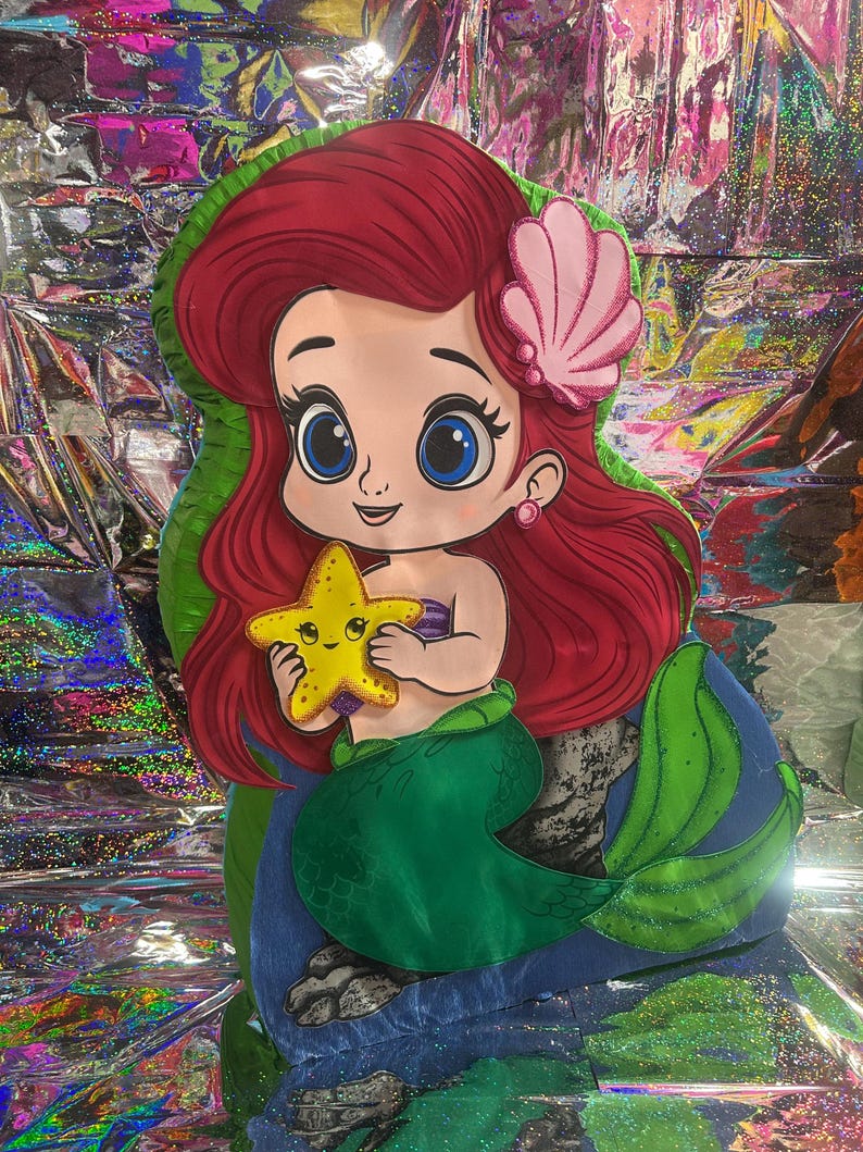 May include: A cartoon illustration of a mermaid with red hair, a pink seashell hair accessory, and a green tail. She is holding a yellow starfish. The mermaid is set against a colorful, iridescent background.