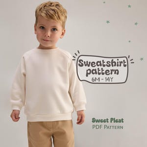 Peut inclure: Un enfant porte un sweat-shirt crème et un pantalon beige. Le sweat-shirt a des manches longues et un col rond. Le texte sur l'image indique "Sweatshirt pattern 6M-14Y" et "Sweet Pleat PDF Pattern". L'arrière-plan est gris clair.