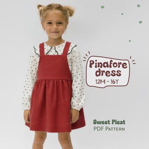 Può includere: Una persona giovane indossa un vestito a grembiule rosso sopra una camicia bianca a maniche lunghe a pois. L'immagine include il testo "Pinafore dress 12M - 16Y" e "Sweet Pleat PDF Pattern".