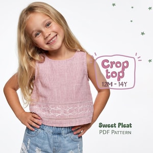 May include: A light pink crop top with a white embroidered hem. The text "Crop top 12M-14Y" is in a pink bubble. The words "Sweet Pleat PDF Pattern" are below the bubble. The girl is wearing denim shorts. The top is sleeveless.