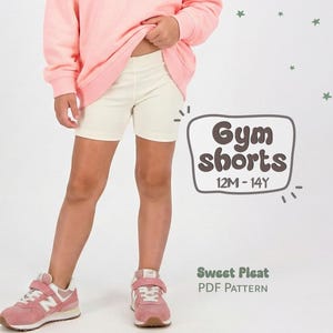 May include: A person wearing a light pink sweatshirt and cream-colored gym shorts. The shorts are knee-length. The image includes the text "Gym shorts 12M-14Y" and "Sweet Pleat PDF Pattern". The person is wearing pink sneakers.