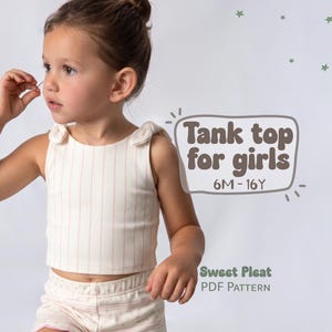 May include: A cream-colored ribbed tank top with thin vertical pink stripes and tied shoulder straps. The text on the image reads Tank top for girls 6M-16Y and Sweet Pleat PDF Pattern. The garment is paired with matching patterned shorts.