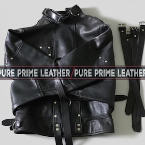 Może przedstawiać: Czarna skórzana kurtka z wieloma paskami i klamrami. Kurtka ma wysoki kołnierz i srebrne okucia. Tekst "PURE PRIME LEATHER" jest wyświetlany.