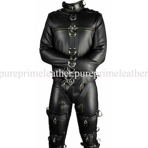Könnte beinhalten: Schwarzes Lederjacken- und Hosen-Set. Die Jacke hat einen hohen Kragen, mehrere Metallringe und einen Reißverschluss. Die Hose hat Reißverschlüsse und Riemen mit Metallbeschlägen. Das Set ist für eine bestimmte Ästhetik konzipiert.