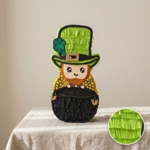 Può includere: Una pignatta a tema San Patrizio a forma di folletto. Il folletto ha un cappello verde con un trifoglio, una barba rossa e un pentolone d'oro. Il pentolone è nero e ha manici dorati. La pignatta è fatta di carta e decorata con frange.