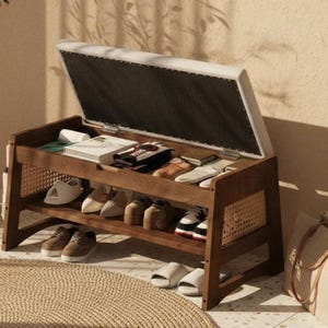 May include: A wooden shoe storage bench with a lift-top cushioned seat. The bench has two open shelves and woven rattan side panels. Various shoes and accessories are stored inside and on the shelves. The bench sits on a woven rug.