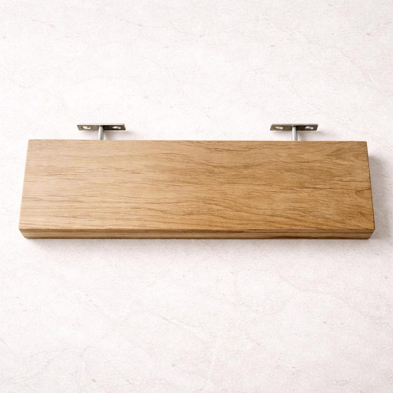 Puede incluir: Una estanter&iacute;a rectangular de madera con un acabado de vetas naturales. La estanter&iacute;a est&aacute; soportada por dos soportes met&aacute;licos. La estanter&iacute;a mide aproximadamente 61 cm de largo y 15 cm de ancho.