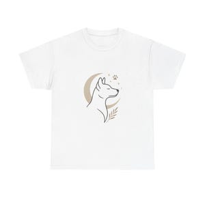 May include: White t-shirt with a minimalist line drawing of a dog's profile inside a crescent moon, with a paw print and stars. The design is in shades of brown and tan. A sprig of leaves is below the dog.
