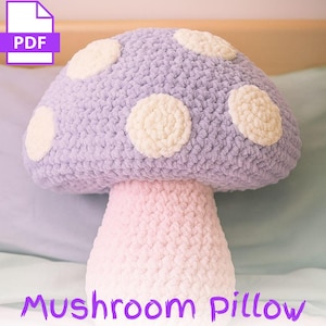 May include: A large, handmade mushroom pillow in shades of lavender, pink, and cream. The mushroom cap is lavender with cream-colored spots, and the stem is pink. The text "Mushroom Pillow" is written in purple at the bottom. A PDF icon is in the top left corner.