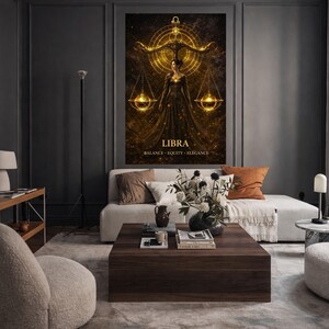 May include: A Libra zodiac sign art print. The artwork features a woman in a flowing gown, holding scales, with the word "LIBRA" below. The print has a gold and black color scheme and is displayed in a modern living room setting.